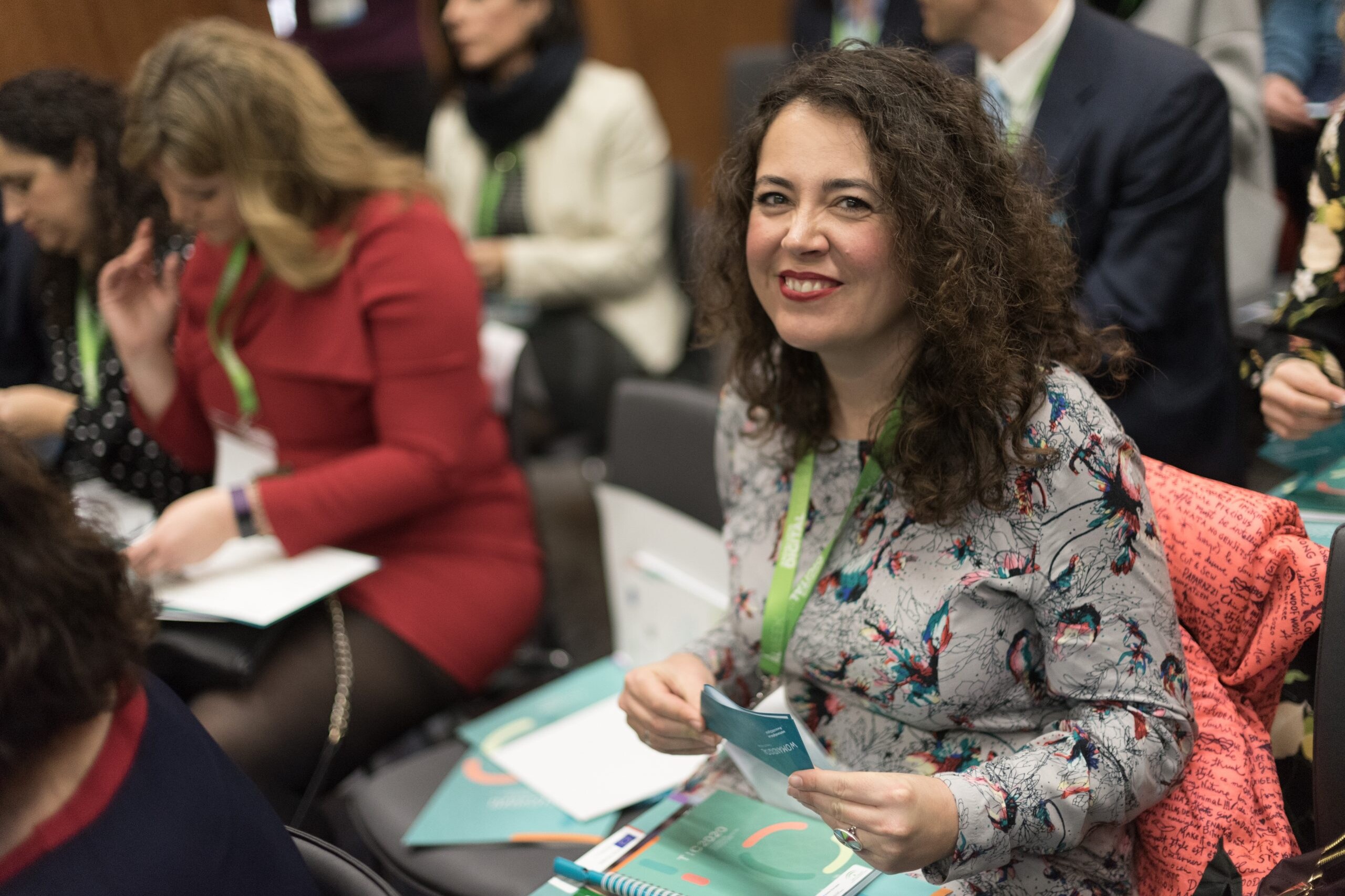 Una mujer sonriendo junto a otras personas que escuchan una charla