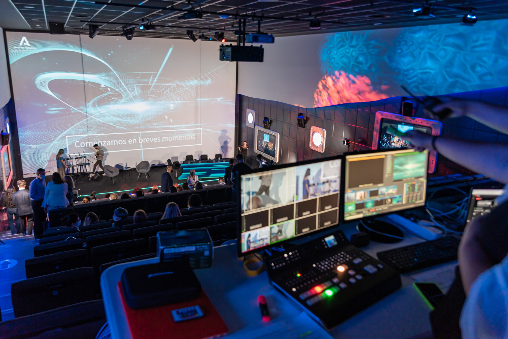 Mesa de control de sonido, luces y proyección del auditorio, al fondo se ve el escenario y una pantalla