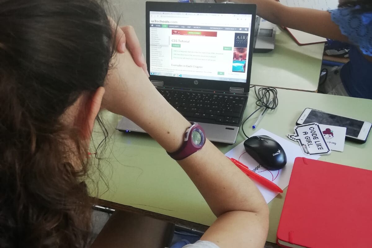 En un aula, una chica mira una página web en la pantalla de un ordenador portátil