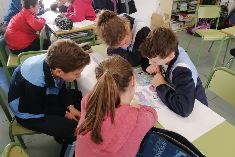 Varios alumnos en un aula leen en un pupitre
