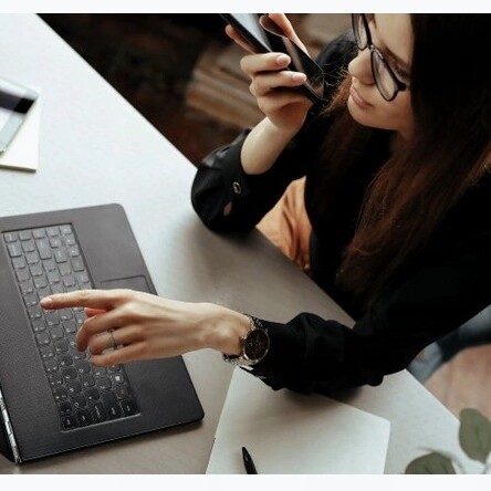 mujer hablando por el movil mientras escribe en un portatil