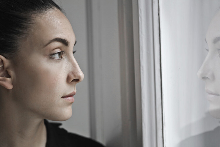 mujer observa su reflejo en una ventana