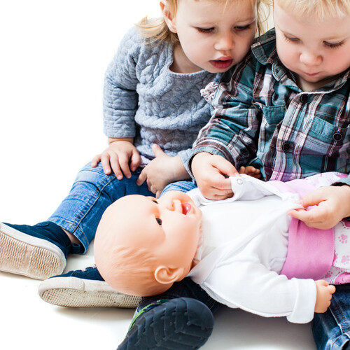 dos niños pequeños jugando con una muñeca