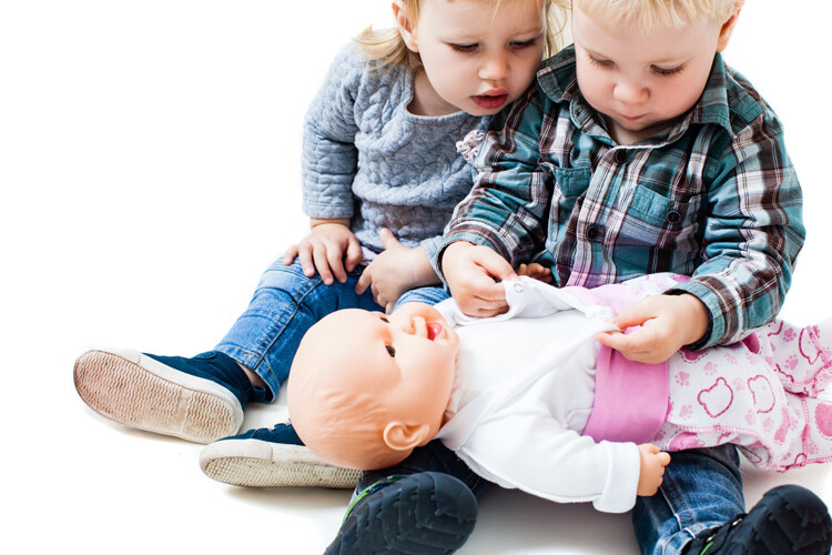 dos niños pequeños jugando con una muñeca