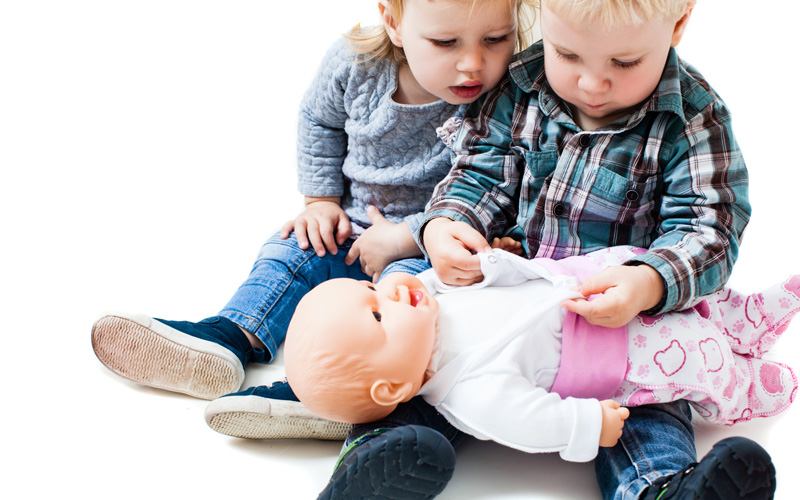 dos niños pequeños jugando con una muñeca