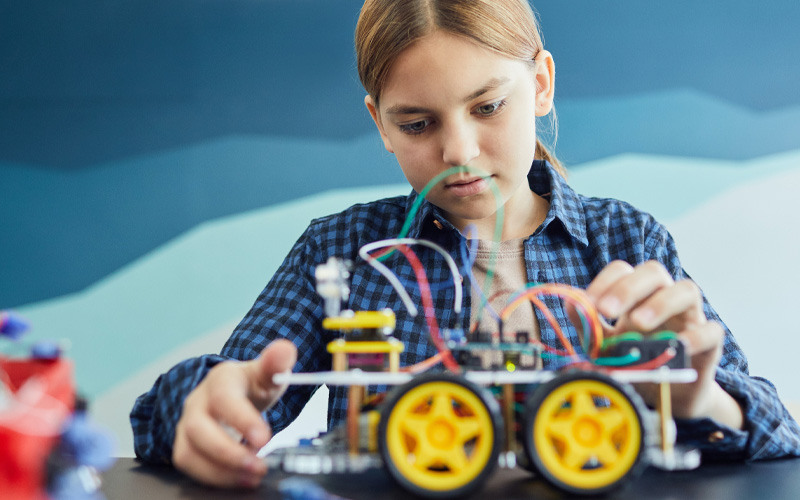 niña construyendo un coche con piezas de lego y electrónica