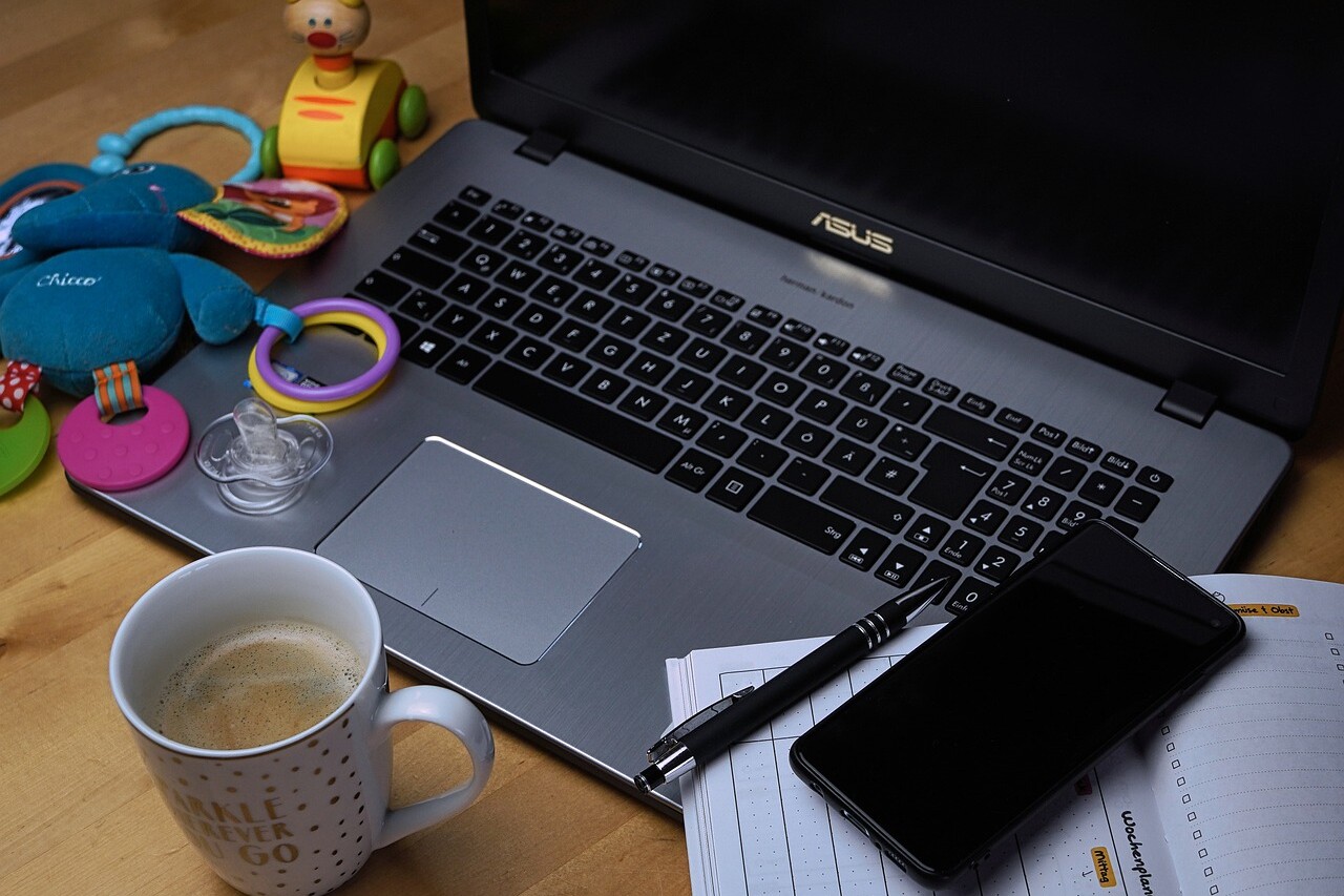 portatil con taza de café y juegues infantiles al lado